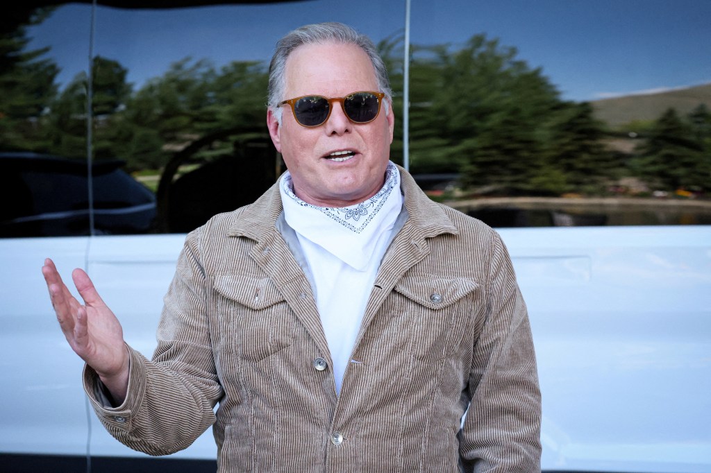 David Zaslav, CEO of Warner Bros. Discovery, speaking to the press after arriving at the Sun Valley Media and Technology Conference, wearing sunglasses and a striped jacket